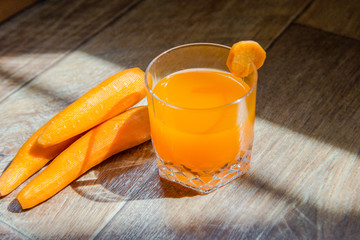 Carrot juice. Healthy food, healthy drink. Orange juice in a glass and next  peeled carrots. healthy eating for breakfast. Wood background