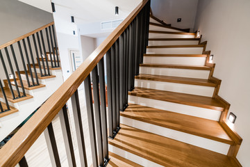stylish wooden stairs in the apartment with handmade black metal railings