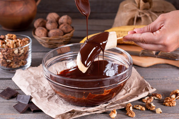 Woman hands pour frozen banana with chocolate. Frozen