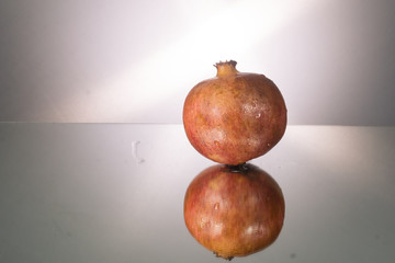 Red pomegranate on mirroring table. Gorizontal image with copy space.
