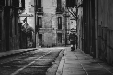 Worker clean public concrete floor with vacuum cleaner. Worker use leaf blower clean sidewalk in the city. Janitor blowing dust on sidewalk. Old architecture in Europe. Narrow alley and building.