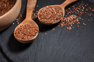 Flax seeds and a wooden spoon on a dark table. Healthy food and drink concept. Top View.