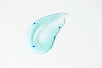 Smear of blue shower gel with scrub grain on white background, top view. Close-up texture peeling cosmetic product. Beauty skin care treatment