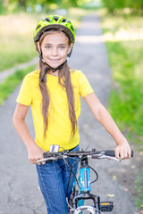 Portrait of a little happy girl with her bike,  looking at camera and smiling