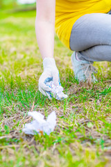 Close up hand picking up garbage in a park. Volunteer and ecology concept