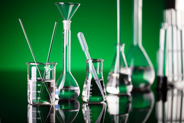 Coronavirus pandemic theme. Science research concerning fast covid tests and anti-covid vaccine. Beakers and test tubes on green background in laboratory.