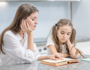 Fototapeta premium Mother and her daughter read a book together at home
