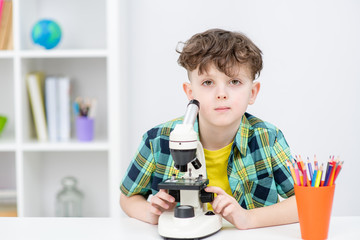 Portrait of a young boy with microscope at home
