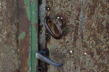 Vintage handle on the door. The old iron door. Metal gate. Cracked paint.