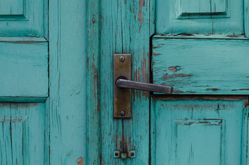 Vintage handle on an old wooden door. The structure of the old tree. Cracked paint.