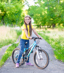 Portrait of a young happy girl standing with her bike in a summer park. Activity leisure concept