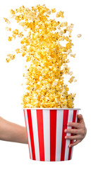 Woman hand holding striped bucket with flying popcorn isolated on white