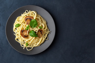 Spaghetti with mushrooms and creamy garlic sauce on a dark background