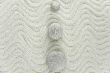Zen garden. Pyramids of white and gray zen stones on the white sand with abstract wave drawings. Concept of harmony, balance and meditation, spa, massage, relax.