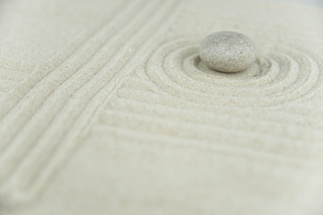 Zen garden. Pyramids of white and gray zen stones on the white sand with abstract wave drawings....
