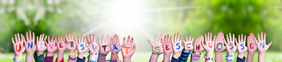 Children Hands Building Colorful German Word Universitaet Geschlossen Means University Closed. Sunny Green Grass Meadow As Background