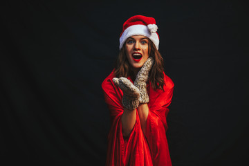 woman in red dress. Santa hat. Christmas woman. Dark background. Santa hat. 