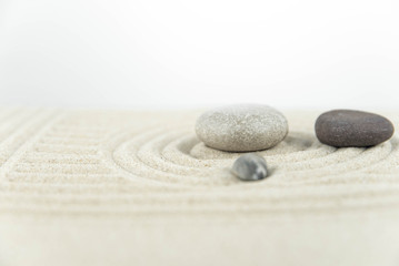 Fototapeta premium Zen garden. Pyramids of white and gray zen stones on the white sand with abstract wave drawings. Concept of harmony, balance and meditation, spa, massage, relax.