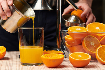 Squeezing an orange with a manual press, close view, making a glass of fresh. Fresh oranges on a...