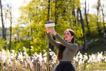 Naklejka premium on a sunny and windy day young smiling emotional brunette receives a surprise gift delivered by quadcopter, concept of modern fast delivery method