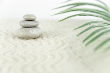 Fototapeta na wymiar Zen garden. Pyramids of white and gray zen stones on the white sand with abstract wave drawings. Concept of harmony, balance and meditation, spa, massage, relax.