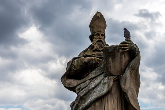 Würzburg, Germany - 10th May 2020: A german photographer visiting the city center, taking pictures of religious statues on the footbridge called old Maria bridge at a cloudy day in spring.
