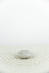 Zen garden. Pyramids of white and gray zen stones on the white sand with abstract wave drawings....