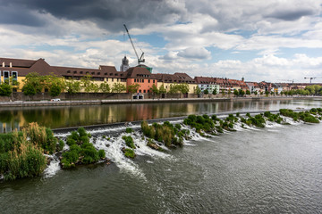 Würzburg, Germany - 10th May 2020: A german photographer visiting the city center, taking pictures on the footbridge called old Maria bridge at a cloudy day in spring.