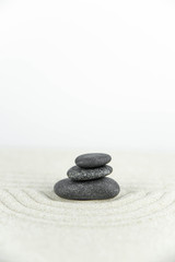 Obraz na płótnie Canvas Zen garden. Pyramids of white and gray zen stones on the white sand with abstract wave drawings. Concept of harmony, balance and meditation, spa, massage, relax.
