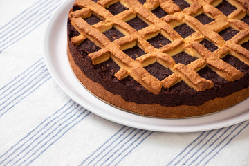 Close-up of fresh poppy cake served on the plate. Homemade poppy seed cake lay on a table with tablecloth. Round, fresh pie, ready to eat.