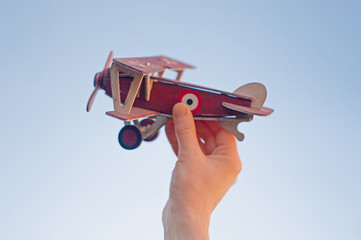 toy plane in hand against the blue sky