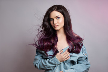 Portrait of a woman with bright colored flying hair, all shades of purple. Hair coloring, beautiful lips and makeup. Hair fluttering in the wind. Sexy girl with long hair styling
