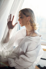 Naklejka premium Blonde women with jewelry earrings in their ears in the rays of the evening sun. Beauty face long hair clean smooth skin, natural cosmetics and makeup