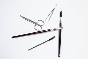 Makeup brushes, scissors, tweezers, mascara on a white background. Makeup. Beauty and fashion.