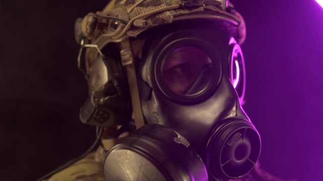 A military soldier in modern equipment and a gas mask holds a rifle in his hands. The concept of war in the modern world, warfare. Slow motion