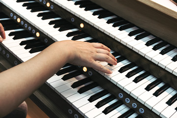 A female pianist plays a three- manual electronic organ.