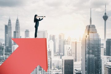 Businesswoman standing on red arrow and using telescope