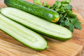 Whole and halves long cucumbers on cutting board close-up