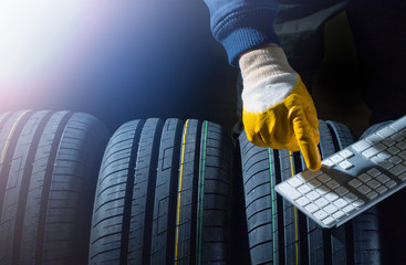 New tires search concept with worker hands and computer keyboard and set of new tires.