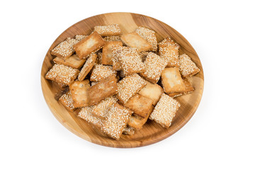 Flat flaky sesame cookies on the wooden dish