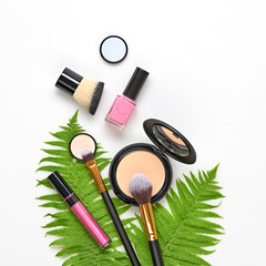 Beauty cosmetic makeup background. Fashion woman make up product, brushes, lipstick, tropical leaf, flat lay. Creative concept. Cosmetology make-up accessories on white, top view.