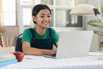 Happy asian girl learning online at home
