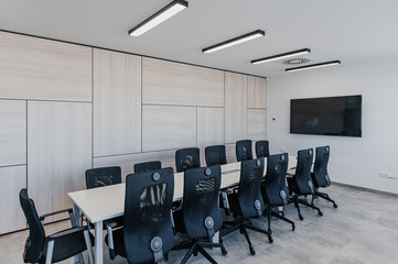 Interior of modern meeting room with office chairs and tv screen and wooden wall