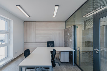 Interior of small new empty office space with desks and chairs and glass wall