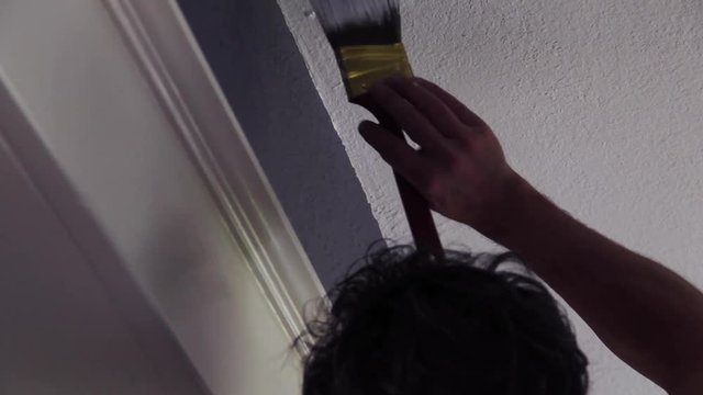 Man carefully paints a white ceiling in an old house