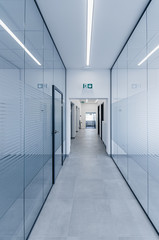 Empty modern hall corridor between glass walls in office building
