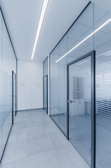 Empty modern hall corridor between glass walls in office building
