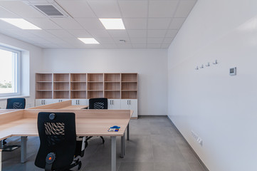 Interior of small new empty office space with desks and chairs