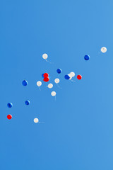 Multicolored helium balloons flying up in the blue sky