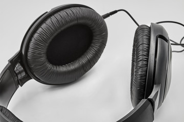 Black headphones lie on white background. Closeup